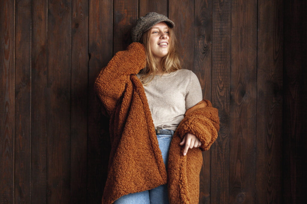 Trench, teddy, cappotto. Gli "immancabili" nella stagione autunno-inverno 4 Trench, teddy, cappotto. Gli "immancabili" nella stagione autunno-inverno - Be Sicily Mag - medium shot smiley woman posing with wooden background
